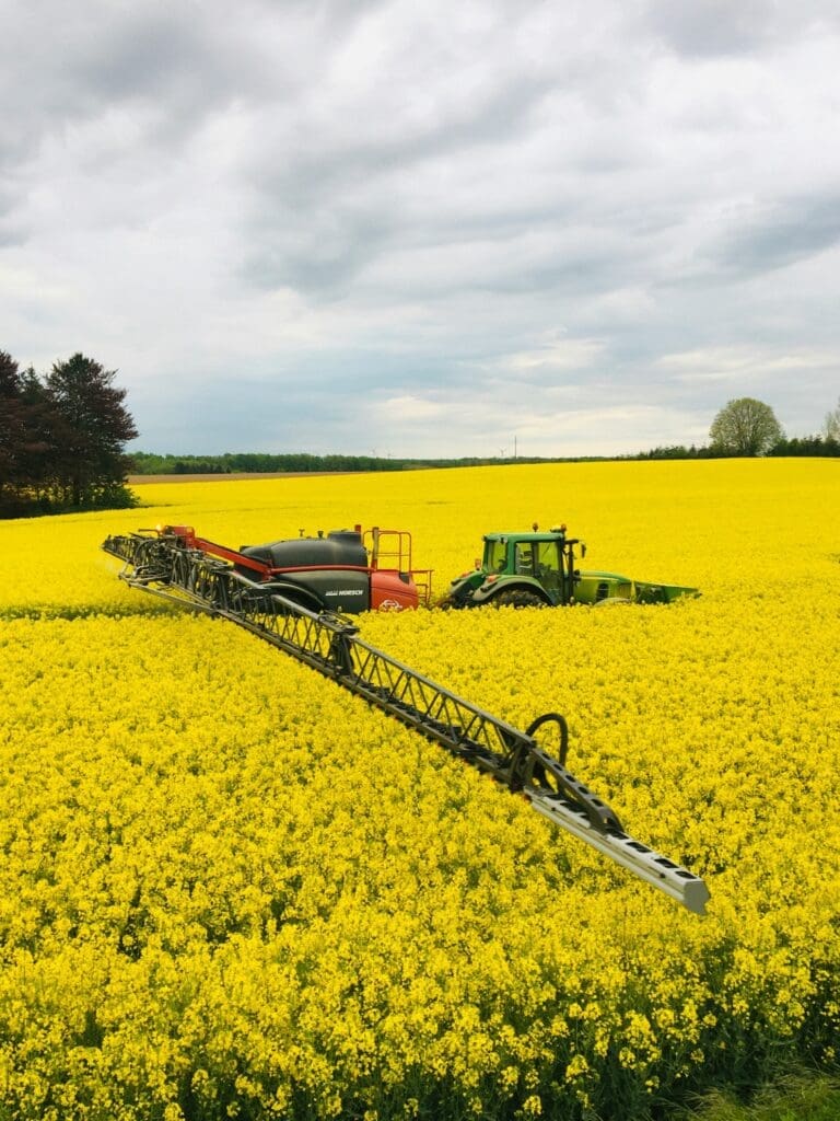 En grøn traktor med en avanceret Horsch marksprøjte i en gul rapsmark, der demonstrerer maskinkonstruktion og automation