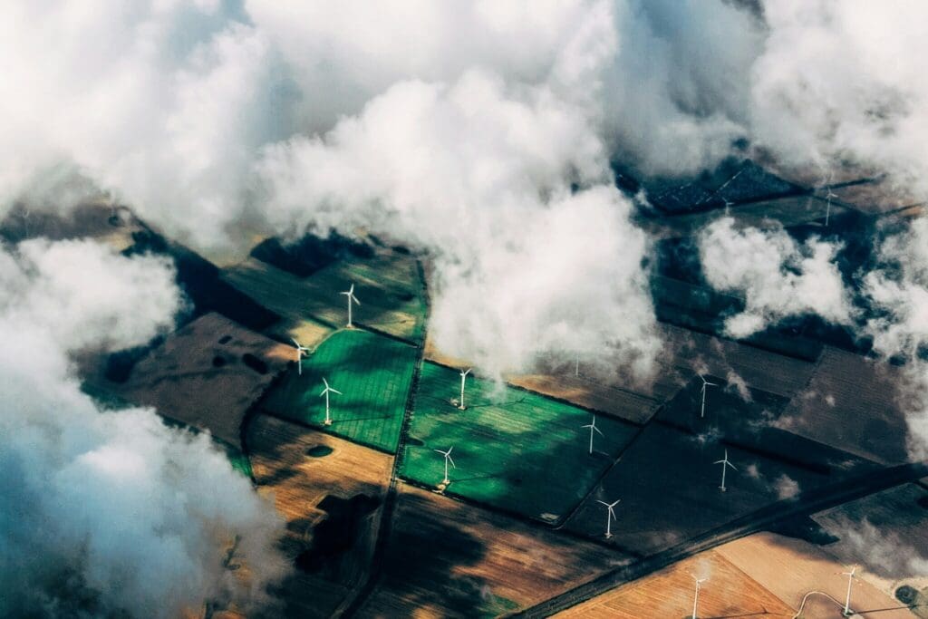 Luftfoto af vindmøller og grønne marker set gennem skyer, der symboliserer Phidan Engineerings fokus på energi, landbrug og grøn omstilling.