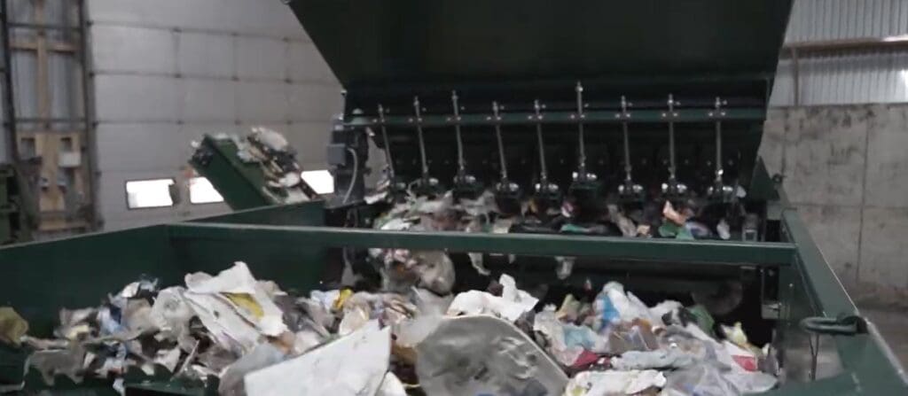 Industrielt anlæg til affaldssortering med mekaniske arme, der bearbejder genbrugsmaterialer.
