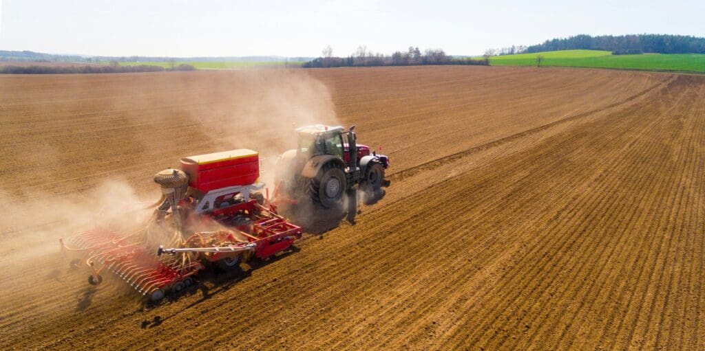 Traktor med avanceret rød såmaskine på marken – eksempel på maskinkonstruktion og landbrugsteknik fra Phidan Engineering.