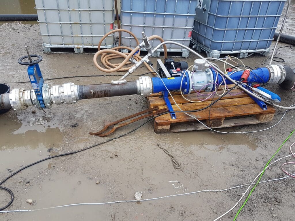 Industriel testopstilling med flowmåler, ventiler og IBC-tanke til biogas- og væsketeknologi udviklet af Phidan Engineering.