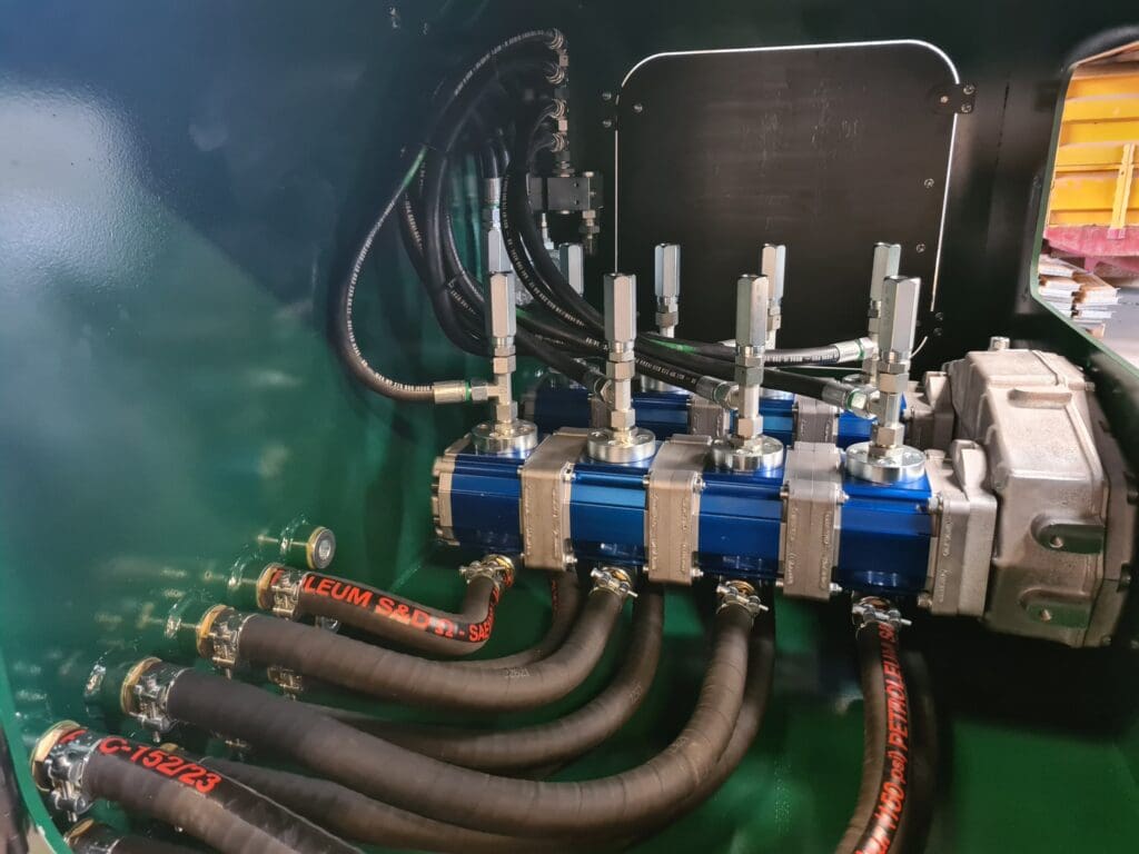 Nærbillede af et komplekst hydraulisk manifold-system med blå pumper og højtryksslanger monteret af Phidan Engineering.