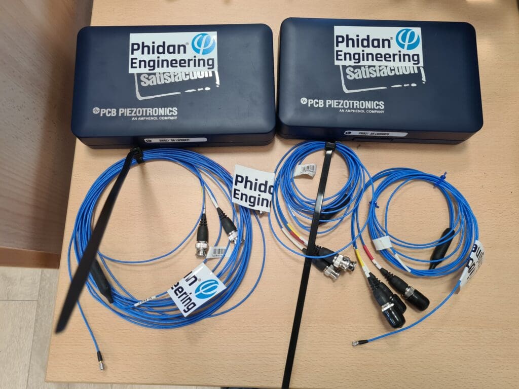 To transportkasser og blåt måleudstyr fra PCB Piezotronics til vibrationsmåling og støjanalyse hos Phidan Engineering.