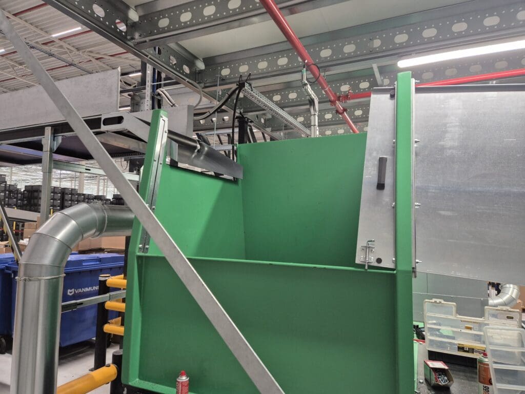 Grøn metalbeholder og specialbygget maskinkonstruktion i et industrielt produktionsmiljø udviklet af Phidan Engineering.