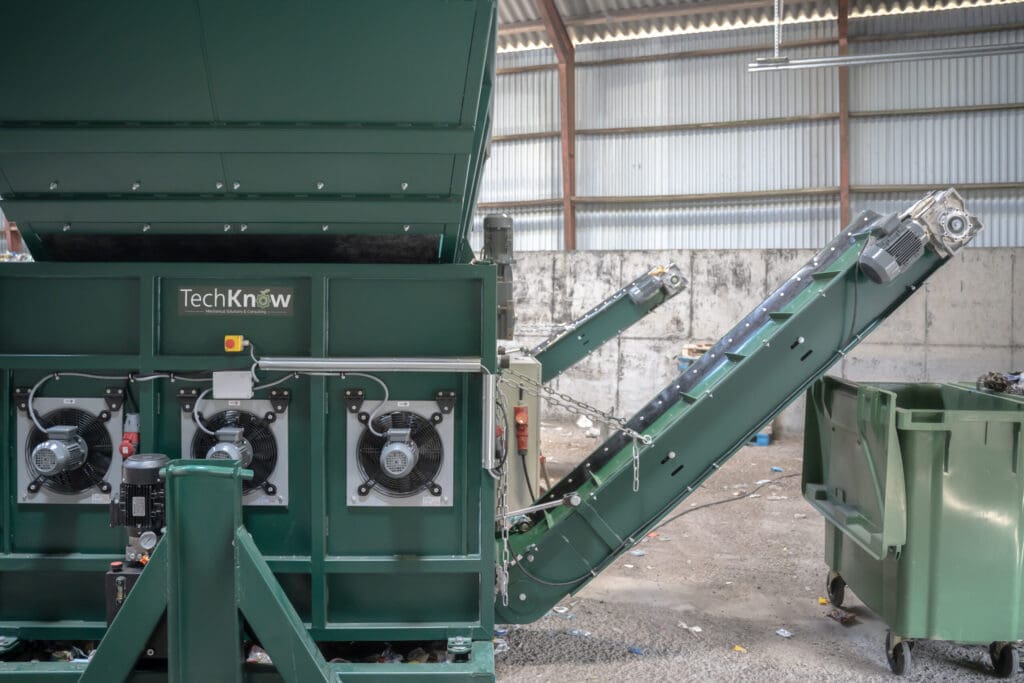 Grøn industriel maskine til recycling med transportbånd, udviklet af Phidan Engineering gennem professionel maskinkonstruktion og CAD.