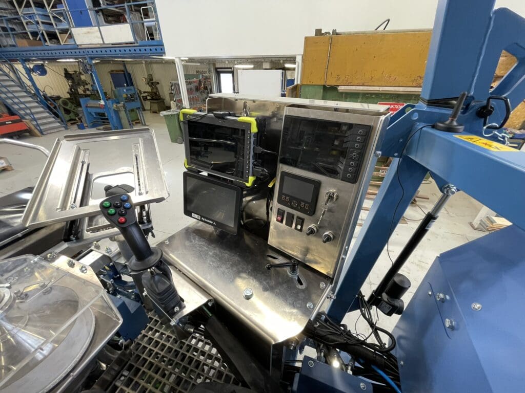 Detaljeret visning af et avanceret cockpit til en specialmaskine med Ag Leader skærme, joystick og kontrolpanel, udviklet af Phidan Engineering.