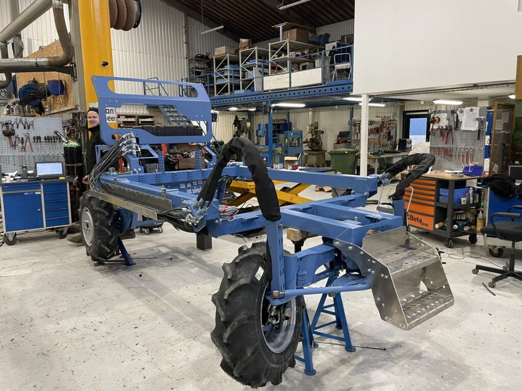 Specialbygget blåt maskinchassis under konstruktion i et værksted med fokus på hydraulik og mekanisk design