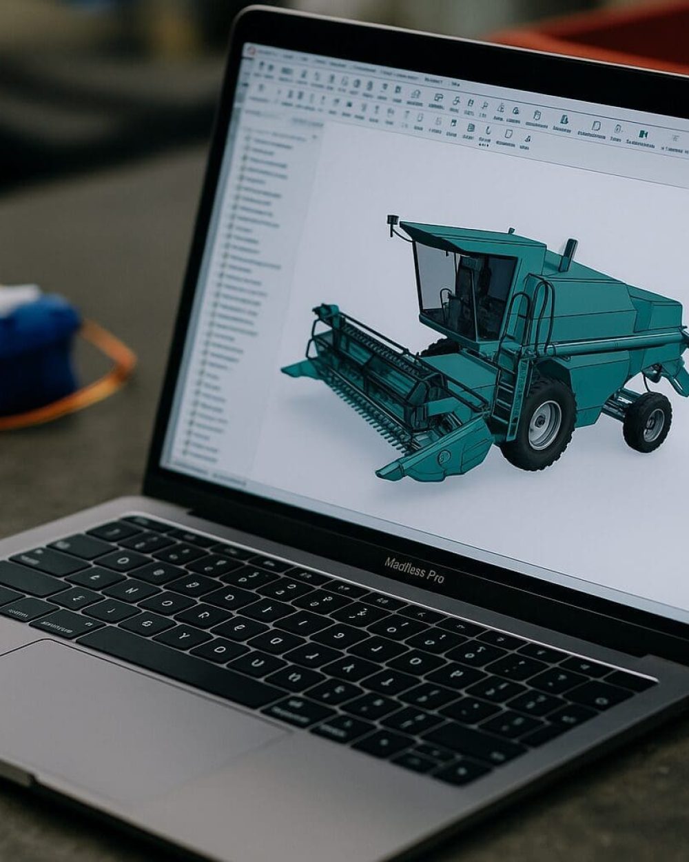 CAD-konstruktion og maskindesign hos Phidan Engineering Bærbar computer med en 3D CAD-model af en grøn mejetærsker, der illustrerer mekanisk konstruktion og produktudvikling til landbrug.