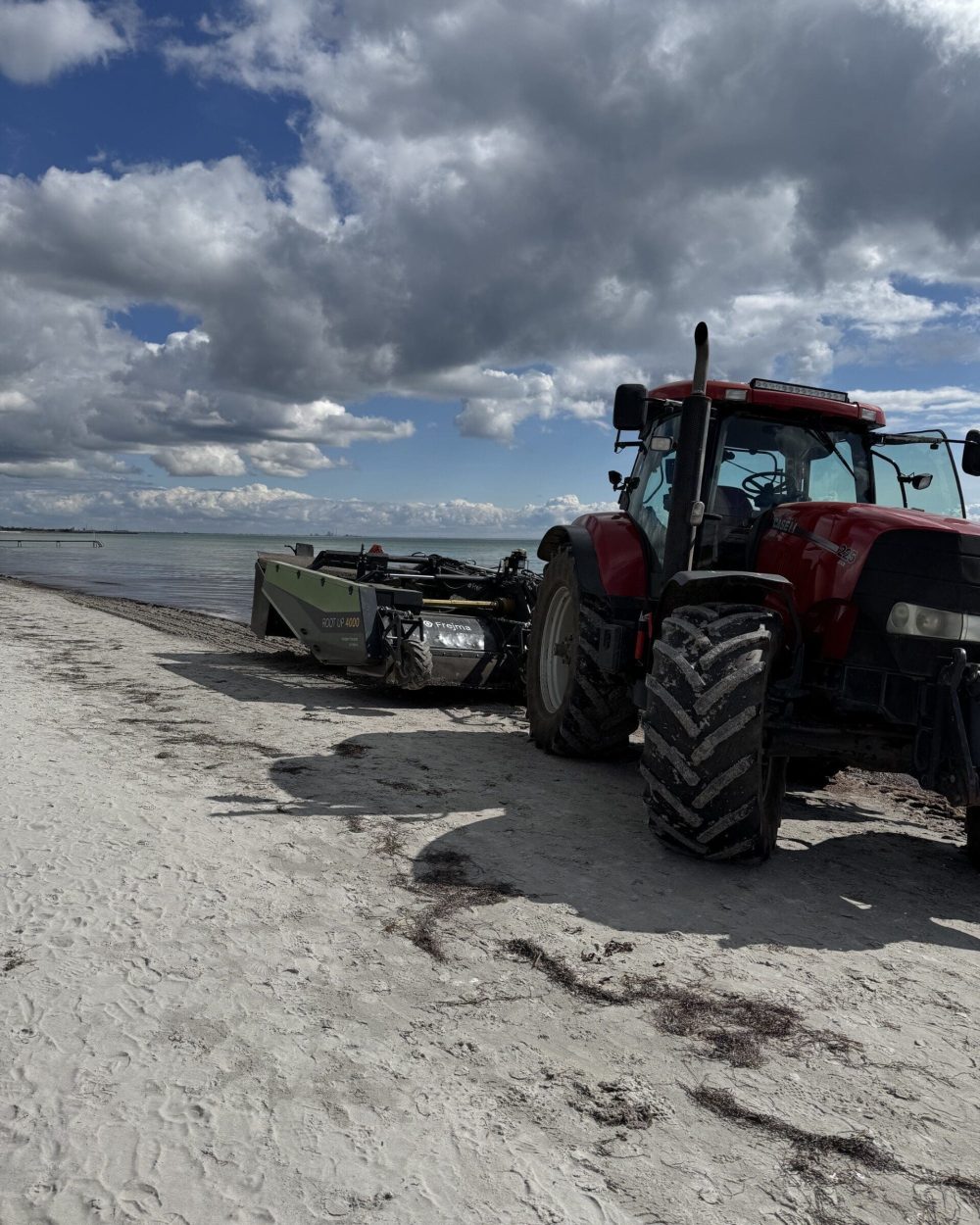 Phidan Engineering: Udvikling og fieldtest af Frejma strandrenser Rød Case IH traktor med en Frejma Root Up 4000 strandrenser på en sandstrand under test – maskinkonstruktion af Phidan Engineering.